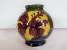 Moorcroft Pottery - a miniature Moorcroft Pottery globular vase in the Hibiscus pattern on a green