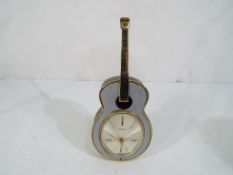 A good quality Swiza retro clock in the form of a guitar with windup movement, approx height 17.