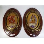 Two ceramic wall plaques decorated with images of artists with brass surrounds mounted on oval