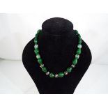 A necklace of green glass pear shaped beads interspersed with spherical hand decorated examples,