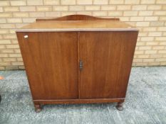 A chest of three drawers enclosed behind doors,