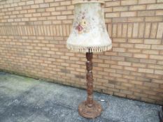 A heavily carved fruitwood standard lamp with shade,
