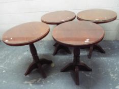 A set of four glass topped wooden bar ta