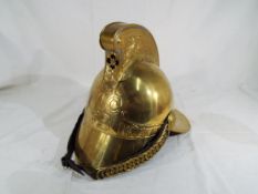 A Victorian brass Merryweather type Fireman's helmet having a leather and brass chin strap and