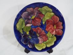 Moorcroft pottery - a large Moorcroft pottery charger decorated with clematis on a blue ground,
