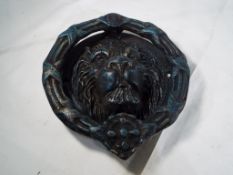 A large cast iron door knocker in the form of a lions head,