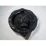 A large cast iron door knocker in the form of a lions head,