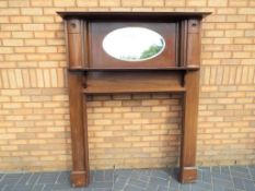 A mahogany fire surround with over-mantel bevel-edged oval mirror,