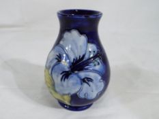 Moorcroft pottery - a small Moorcroft pottery vase decorated with blue hibiscus on a blue ground,
