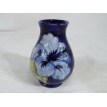 Moorcroft pottery - a small Moorcroft pottery vase decorated with blue hibiscus on a blue ground,