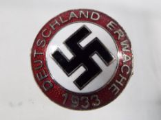 A white metal enamelled pin badge displa