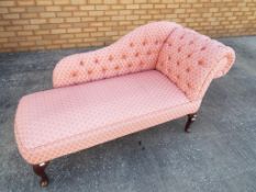 A pink chaise lounge on wooden legs approx 77cm x 137cm x 56cm
