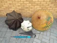 A collection of parasols to include wood and paper construction,