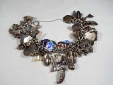 A sterling silver charms bracelet containing 64 silver and enamelled charms,