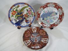 Three Asian plates comprising one in the Imari pattern with character marks to the base,