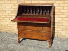 An oak bureau, the slope front opening to reveal a fitted interior, above three graduated drawers,