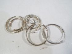 Four pairs of silver hooped earrings.