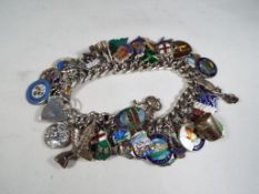 A sterling silver charm bracelet containing 56 silver and predominantly enamelled charms,
