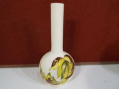 Moorcroft Pottery - A Moorcroft pottery bud vase decorated with the Leaves in the Wind pattern on a