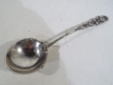 A silver ladle with a floral decorated h