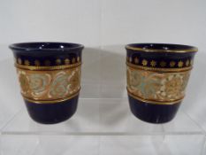 Royal Doulton - a pair of Royal Doulton stoneware vases with relief decoration and gilded