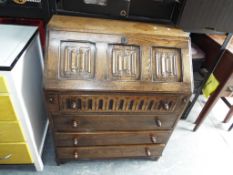 An oak slope front bureau over four drawers, pigeon-hole fitted interior,