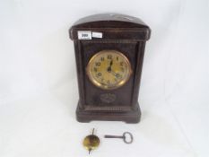 An oak cased mantel clock with carved decoration, Arabic numerals to the dial,