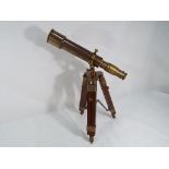 A brass telescope on wooden tripod stand.