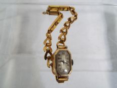 A lady's 9 ct gold wrist watch stamped 375 on a rolled gold bracelet, Arabic numerals to the dial.
