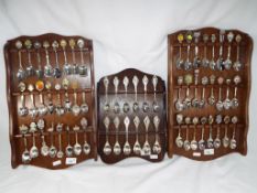 Three wooden wall mounted display cases containing sixty plated souvenir spoons (3) This lot MUST
