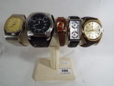 A watch display stand containing five watches to include Lorus, Sandoz, Sekonda, FCUK and Genicko.