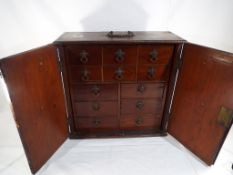 A good quality mahogany apprentice two door cabinet opening to reveal drawers with drop handles,