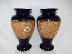 Royal Doulton - a pair of Royal Doulton stoneware vases on a blue ground with relief decoration and
