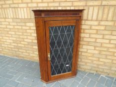 An oak wall-mounted corner cabinet with