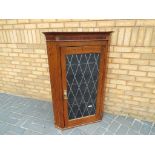 An oak wall-mounted corner cabinet with