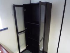 A modern black wooden twin-door display cabinet with glass shelved interior,