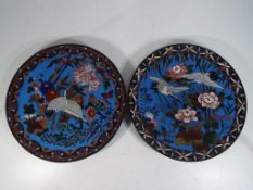 Two Japanese cloisonne plates decorated with flowers and cranes on a blue ground, approximately 30.