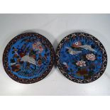 Two Japanese cloisonne plates decorated with flowers and cranes on a blue ground, approximately 30.