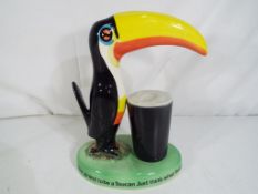 A ceramic lamp base in the form of a Guinness toucan with pint,