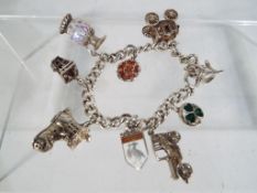A silver hallmarked charm bracelet with nine charms, four of which are stamped silver or hallmarked,