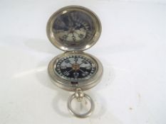 A white metal British military compass marked with crow's foot/wide arrow Stanley London 114452,