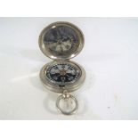 A white metal British military compass marked with crow's foot/wide arrow Stanley London 114452,