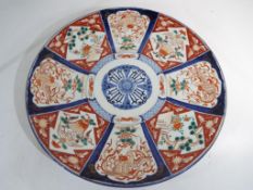 A large ceramic charger decorated in the Imari pattern over eight panels,