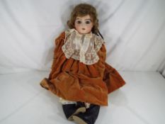 Dolls - A reproduction Bru Jne bisque headed doll with fixed blue glass eyes, pierced ears,