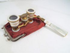 A pair of opera glasses with cream enamelled barrels decorated in gold and red with original