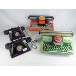 A pair of child's black bakelite battery operated telephones linked by twisted wire cord,