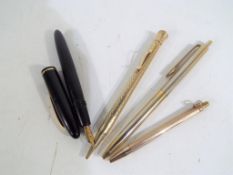 A Bayard fountain pen with an 18 carat gold nib and three gold plated pens and pencils.