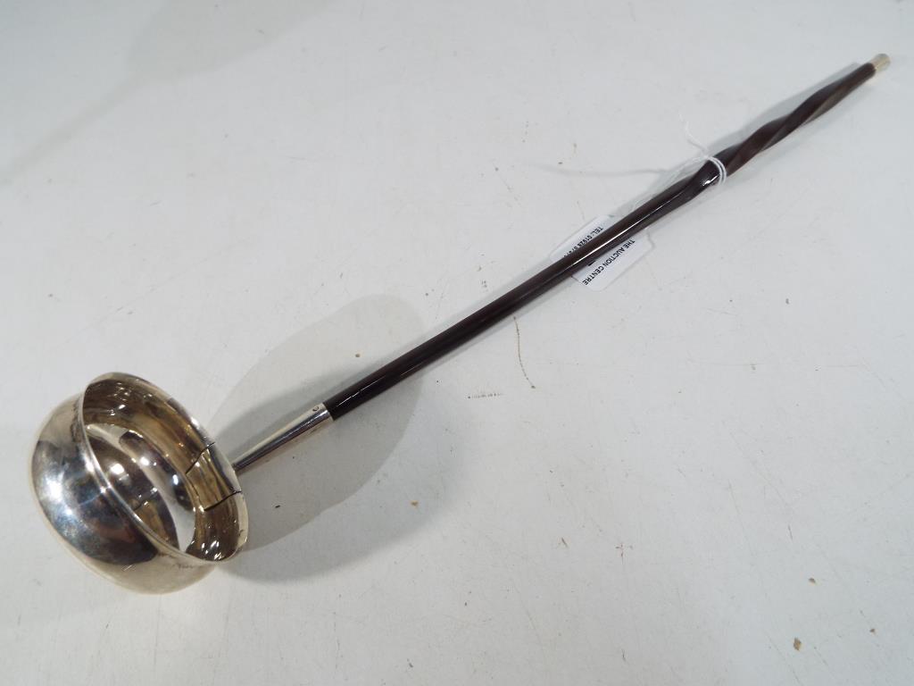 A silver punch ladle with inscribed this