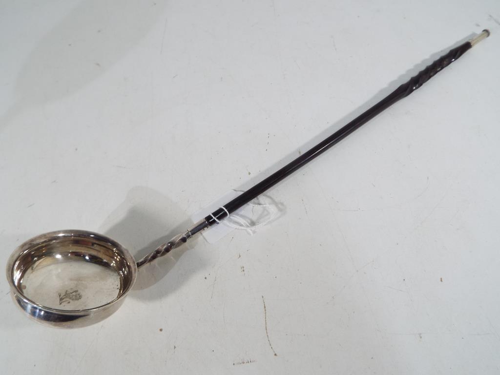 A silver punch ladle with inscribed lion
