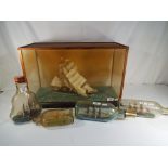 A model ship contained within a display case and 4 ships in bottles.